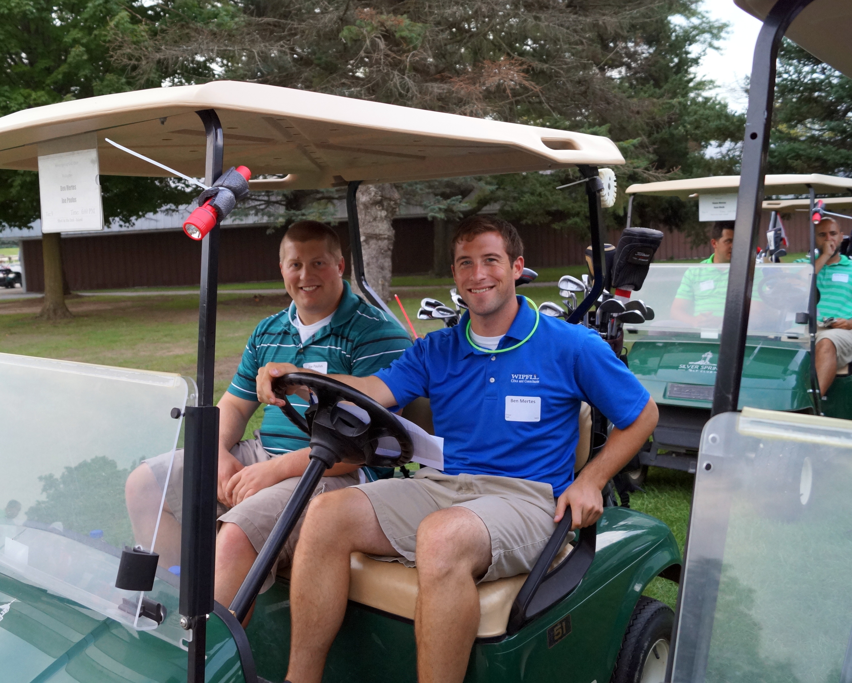 Two young men are very happily sitting in a golf cart.